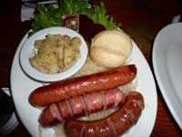 A sausage sampler plate with sauerkraut and potato salad